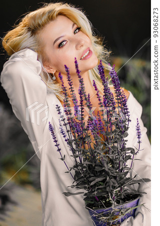 an attractive middle-aged blonde woman topless in a white shirt with lavender.  93068273