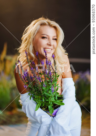 an attractive middle-aged blonde woman topless in a white shirt with lavender.  93068370