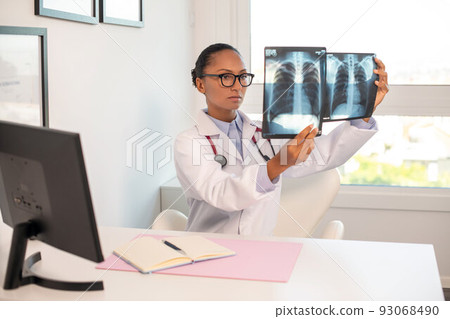 Serious pulmonologist examining x-ray pictures of human lungs 93068490