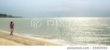 a woman takes picture on the sea beach with smartphone a woman takes picture on the sea beach with smartphone 93069360