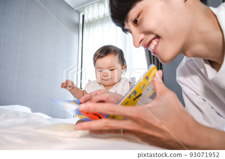 Daddy reading a picture book to her daughter 93071952