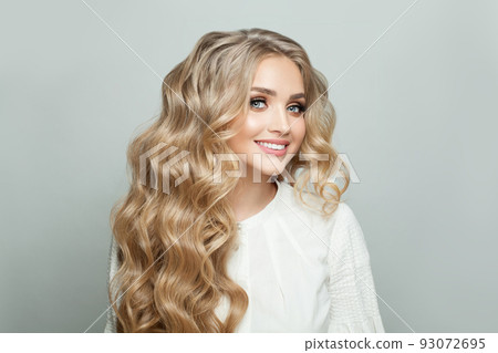 Happy blonde woman with long healthy wavy hair smiling and looking at camera Happy blonde woman with long healthy wavy hair smiling and looking at camera 93072695