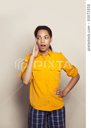 Young beautiful surprised african american woman wearing casual yellow shirt standing Young beautiful surprised african american woman wearing casual yellow shirt standing 93072858