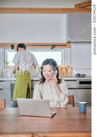 一個在遠程工作中用智能手機打電話的女人和一個做家務的男人 一個在遠程工作中用智能手機打電話的女人和一個做家務的男人 93074429