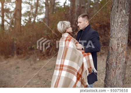 Couple in a field. Girl in a brown coat. Man with his wife in a autumn forest Couple in a field. Girl in a brown coat. Man with his wife in a autumn forest 93075658