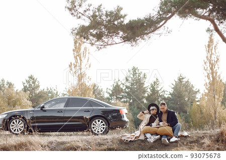 Couple in a field. Girl in a brown coat. Man with his wife near the car 93075678