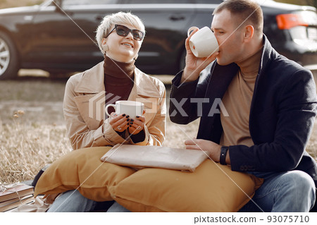 Couple in a field. Girl in a brown coat. Man with his wife near the car 93075710