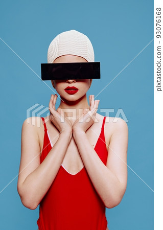Be hidden. Prohibited content. A slender girl in a red swimsuit swimming cap holds her hands showing a sign In on a blue background 93076168