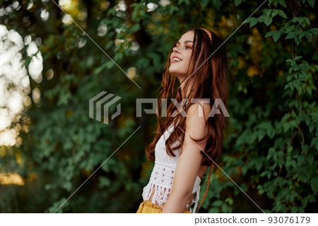 A woman in eco-friendly clothing in a hippie look dances in nature in the park and smiles at the world. The concept of harmony with the body and the surrounding nature 93076179