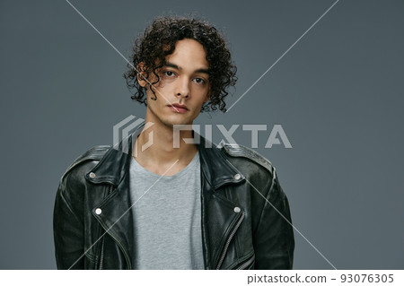 Pretty sexy self-confident stylish tanned curly man leather jacket posing isolated on over gray studio background. Cool fashion offer. Huge Seasonal Sale New Collection concept. Copy space for ad Pretty sexy self-confident stylish tanned curly man leather jacket posing isolated on over gray studio background. Cool fashion offer. Huge Seasonal Sale New Collection concept. Copy space for ad 93076305
