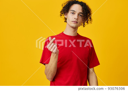 Lovely funny Caucasian young man in red t-shirt show heart shape gesture posing isolated on over yellow studio background. The best offer with free place for advertising. Emotions for everyday concept 93076306