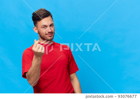 Cute attractive happy smiling tanned handsome man in red t-shirt heart shaped sign with fingers posing isolated on blue studio background. Copy space Banner Mockup. People emotions Lifestyle concept Cute attractive happy smiling tanned handsome man in red t-shirt heart shaped sign with fingers posing isolated on blue studio background. Copy space Banner Mockup. People emotions Lifestyle concept 93076677