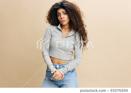 Depressed sad worried caucasian curly woman 20s wearing casual gray t-shirt look to you touch pained arm isolated on plain pastel light beige background studio portrait. People emotions concept Depressed sad worried caucasian curly woman 20s wearing casual gray t-shirt look to you touch pained arm isolated on plain pastel light beige background studio portrait. People emotions concept 93076899