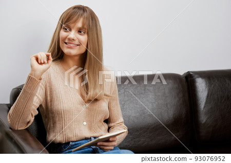 Happy enjoyed blonde student lady with copybook attentively listens to interlocutor sitting in sofa at modern interior. Female client have shrink appointment in psychological help office. Copy space Happy enjoyed blonde student lady with copybook attentively listens to interlocutor sitting in sofa at modern interior. Female client have shrink appointment in psychological help office. Copy space 93076952