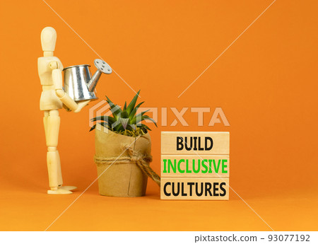 Build inclusive cultures symbol. Concept words Build inclusive cultures on wooden blocks. Businessman model. Beautiful orange background. Business build inclusive cultures concept. Copy space. 93077192
