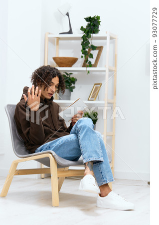 portrait of a man writes in a notebook sitting on a chair in the room isolated background 93077729