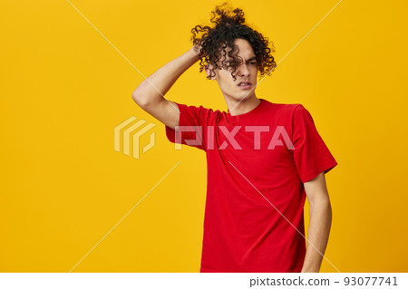 Joyful funny Caucasian young man in red t-shirt touches hair curls posing isolated on over yellow studio background. The best offer with free place for advertising. Emotions for everyday concept Joyful funny Caucasian young man in red t-shirt touches hair curls posing isolated on over yellow studio background. The best offer with free place for advertising. Emotions for everyday concept 93077741