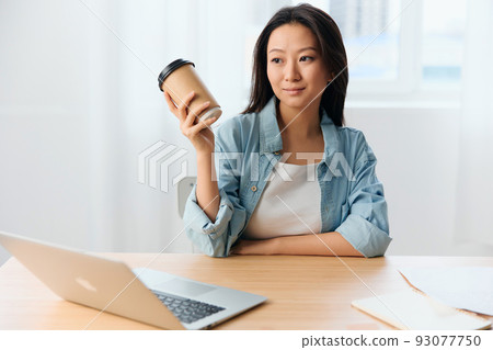 Happy smiling pensive young Asian cute businesswoman hold coffee cup enjoy looks aside in light office interior. Freelancer work at home. Lady corporation leader concept. Copy space Offer Happy smiling pensive young Asian cute businesswoman hold coffee cup enjoy looks aside in light office interior. Freelancer work at home. Lady corporation leader concept. Copy space Offer 93077750