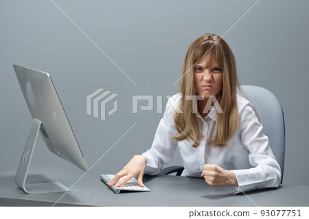 Irritated pretty blonde businesswoman worker freelancer show fist using desktop computer sitting at workplace in gray modern office. Remote Job, Technology And Career Profession Concept. Copy space Irritated pretty blonde businesswoman worker freelancer show fist using desktop computer sitting at workplace in gray modern office. Remote Job, Technology And Career Profession Concept. Copy space 93077751