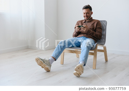 Enjoyed focused confused attractive try to win enthusiastically playing in exciting raising game looks at screen. Happy guy relaxing with phone chatting with friends. Mobile App concept. Copy space 93077759