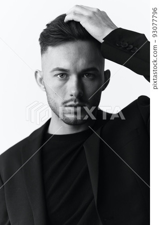 Modelling snapshots. Closeup portrait of self-confident attractive handsome muscular guy man in jacket looks at camera sitting on chair in white studio background. Black and White concept. Copy space 93077796