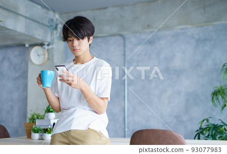 young man looking at smartphone young man looking at smartphone 93077983