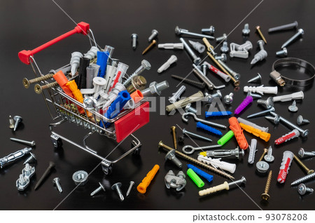 Different types of fasteners in a supermarket trolley. Place for text or logo. Concept: fastener store. Background of dark wood and a lot of fasteners. 93078208