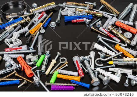 Different types of fasteners on a dark wood background. Front view. Place for text or logo round shaped. 93078216