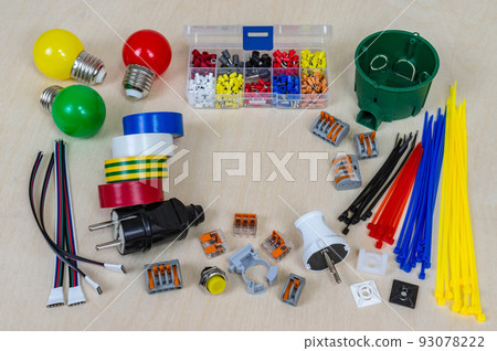 Multi-colored electrical components and parts on a plywood background. Orange, yellow, red, blue, green, white, black, grey. Place for text or logo. Multi-colored electrical components and parts on a plywood background. Orange, yellow, red, blue, green, white, black, grey. Place for text or logo. 93078222