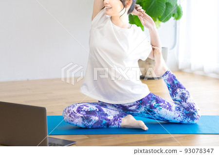 Young woman doing online yoga at home 93078347