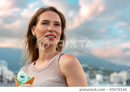 Young woman with ice cream walking in the street Young woman with ice cream walking in the street 93078548