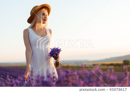 Young woman in long white dress standing in lavender field 93078617