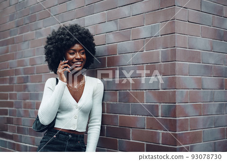 Portrait of happy african young woman talking on cellphone in city 93078730