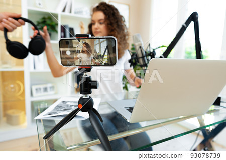Young curly female blogger recording video at table at home 93078739