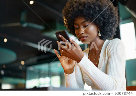 Young afro woman using mobile phone at coffee shop Young afro woman using mobile phone at coffee shop 93078744