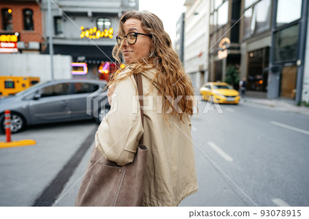 Young beautiful pretty woman walking along the street in modern city 93078915