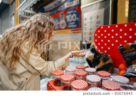 Female petting homeless cat that sits on counter with jars Female petting homeless cat that sits on counter with jars 93078945