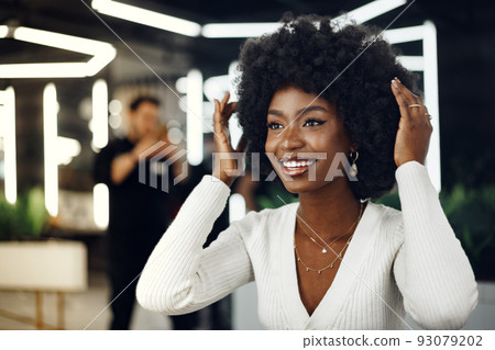 Young african woman customer getting a hairstyle at a beauty salon. Young african woman customer getting a hairstyle at a beauty salon. 93079202