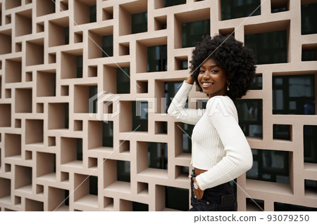 Stylish pretty african woman with Afro hairstyle posing near geometric wall 93079250