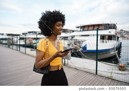 Portrait of a young african american woman smiling standing at the city. 93079303