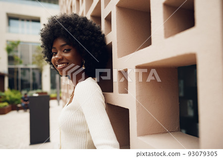 Stylish pretty african woman with Afro hairstyle posing near geometric wall 93079305