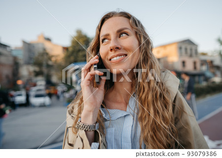Young casual woman talking on the smartphone at the city Young casual woman talking on the smartphone at the city 93079386