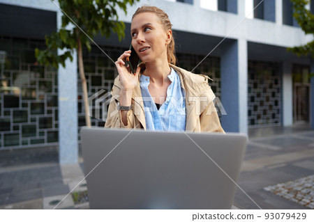 Young beautiful woman working on a laptop sitting on the bench in the street Young beautiful woman working on a laptop sitting on the bench in the street 93079429