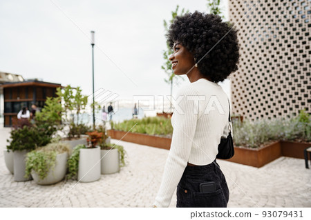 Portrait of attractive young woman walking outside in the city Portrait of attractive young woman walking outside in the city 93079431