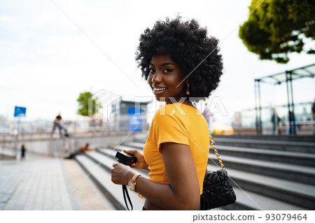 Smiling African american woman using professional camera at a street Smiling African american woman using professional camera at a street 93079464