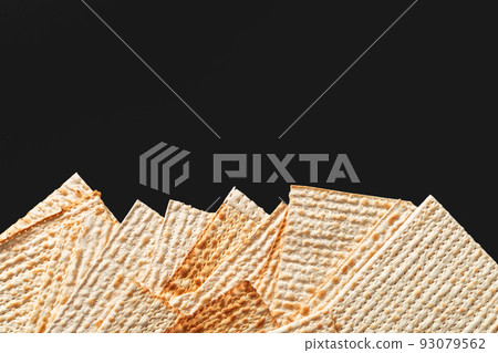 A photo of matzah or matza pieces on black background. Matzah for the Jewish Passover holidays. Place for text, copy space 93079562