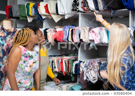 The clothing designer shows her customers the fabrics on the rack. The clothing designer shows her customers the fabrics on the rack. 93080404