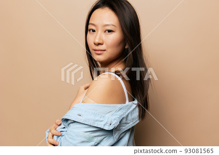 Portrait of happy tanned adorable young Asian lady after vaccination hold shirt sleeve posing isolated on beige pastel background. People Emotions. CoVID Vaccination concept. Copy Space Offer Banner. Portrait of happy tanned adorable young Asian lady after vaccination hold shirt sleeve posing isolated on beige pastel background. People Emotions. CoVID Vaccination concept. Copy Space Offer Banner. 93081565