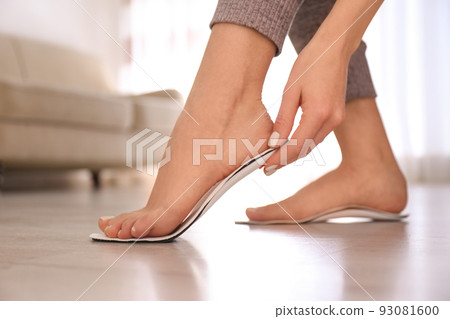 Woman fitting orthopedic insole at home, closeup Woman fitting orthopedic insole at home, closeup 93081600