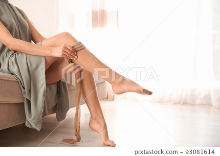Beautiful woman putting on tights indoors, closeup. Space for text Beautiful woman putting on tights indoors, closeup. Space for text 93081614